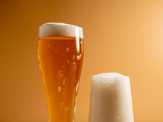 Glass of beer with foam. Mug of beer on an orange background.