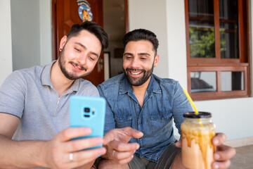 brazilian gay couple looking at mobile screen and smiling outside the house