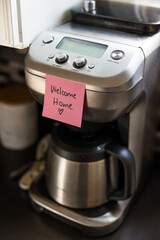 Pink welcome home sticky note on coffee pot