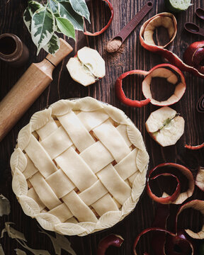 Red apple pie with lattice design in the making on a rustic wooden table