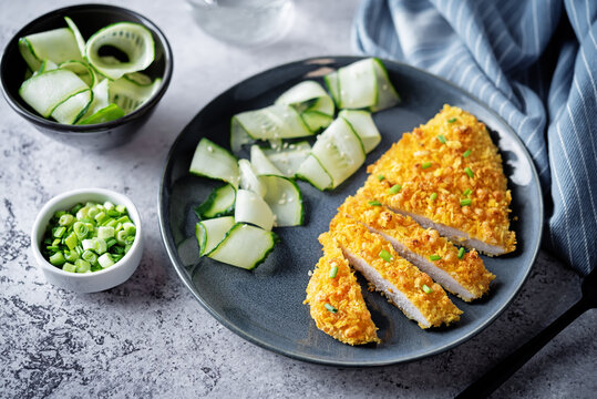 Bread Crumbs Cheesy Chicken Breast With Cucumbers In A Plate