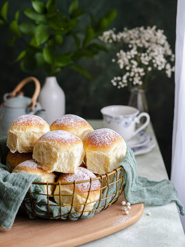 Homemade milk and creamcheese buns in a basket with a cloth next to a window