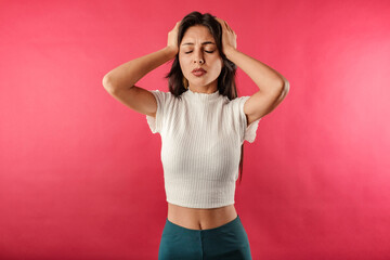 Young beautiful woman wearing ribbed crop isolated over red background hand on head, headache because stress. Suffering migraine.