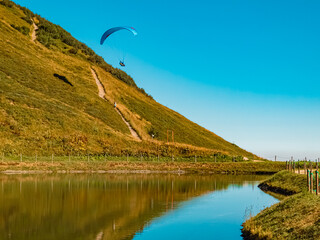Beautiful alpine summer view with reflections in a lake and a paraglider at the famous Kanzelwand...