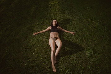 Naklejka premium Slim girl in a leopard bikini and a black top by the pool