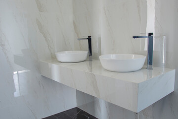 two washbasins with chrome mixer on a marble-topped countertop in a luxury bathroom