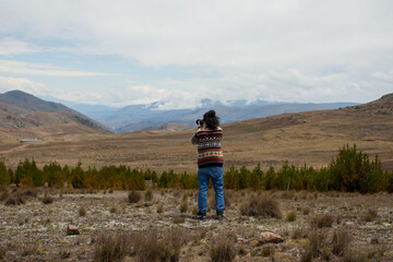 Male tourist in landscape of the Andes of South America with a camera in his hand. Concept of people, travel, tourism.