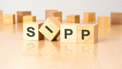 four wooden blocks with text SIPP on table. copy space. white background.
