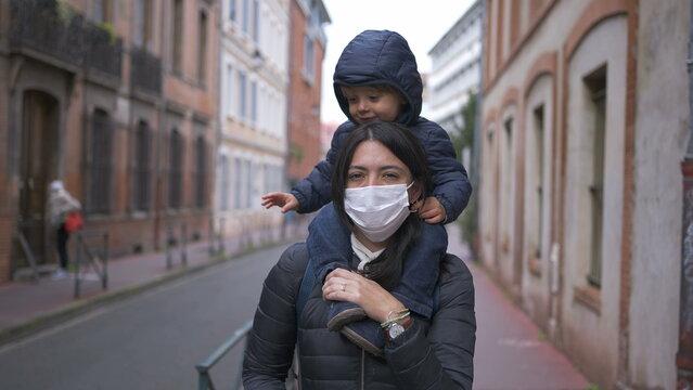 Mother Walking Outside With Toddler In Back Wearing Covid Face Mask