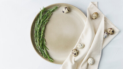 The beige plate stands on a grey close-up background. in the plate lies a wreath of rosemary and boiled quail eggs. minimalism. Easter table decoration, Easter decor, festive decor