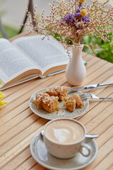 Coffee, dessert and book outside. Vegan doughnut with cup of coffee and book. Atmospheric lunch, time for yourself.