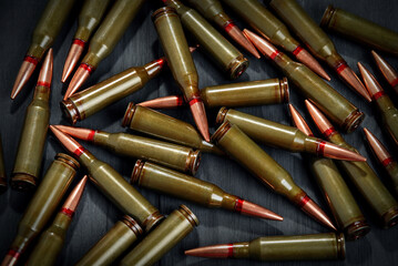 Ammunition for a automatic rifle on dark surface.  Cartridges to AK 74.