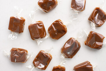 Individually wrapped caramels on a marble countertop. 