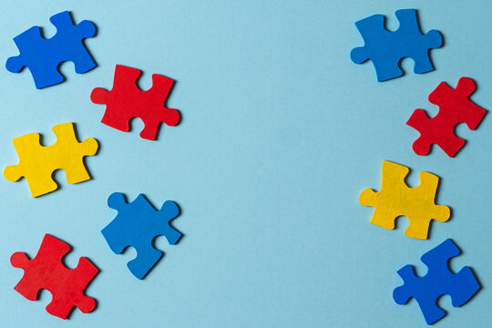 Blue, yellow, red pieces of puzzle on light blue frame background. World autism awareness day concept. Top view, copy space