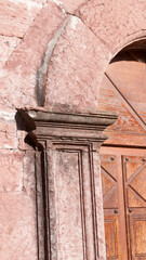 Arco en fachada de pequeña iglesia rural de piedra rosada
