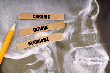 On x-rays of a human skull, a pencil and strips of paper with the inscription - Chronic fatigue...