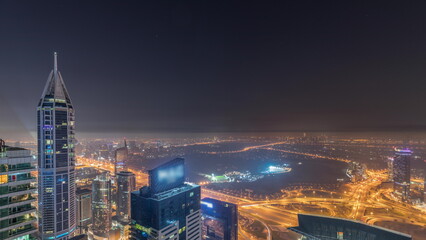 Fototapeta premium Aerial skyline with Golf Club, hotels and residential areas far away in desert in Dubai all night timelapse, UAE, top view