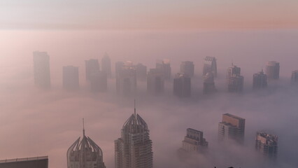 Fog covered JLT skyscrapers and marina towers near Sheikh Zayed Road aerial timelapse during sunrise. Residential buildings