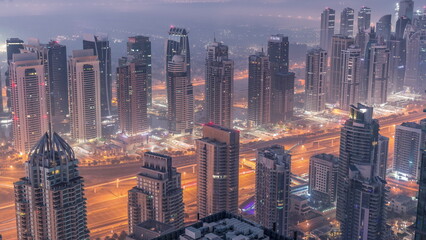 Obraz na płótnie Canvas JLT skyscrapers and marina towers near Sheikh Zayed Road aerial night to day timelapse. Residential buildings