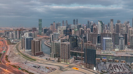 Naklejka premium Skyline with modern architecture of Dubai business bay towers night to day timelapse. Aerial view