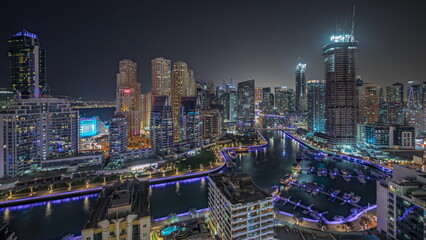 Fototapeta na wymiar Panorama showing Dubai Marina with several boat and yachts parked in harbor and skyscrapers around canal aerial night timelapse.