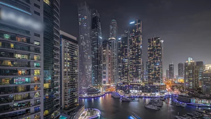 Fotobehang Panorama showing Dubai marina tallest skyscrapers and yachts in harbor aerial night timelapse. © neiezhmakov