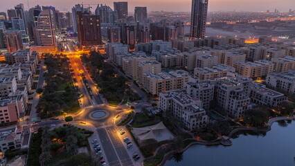 Skyscrapers in Barsha Heights district and low rise buildings in Greens district aerial night to...