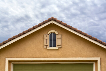 House attic gable window on stucco wall with cloudy sky background, Menifee, California