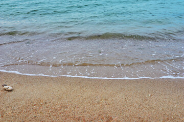 Sea coast and moving wave at the sandy beach for background and inspirational text.