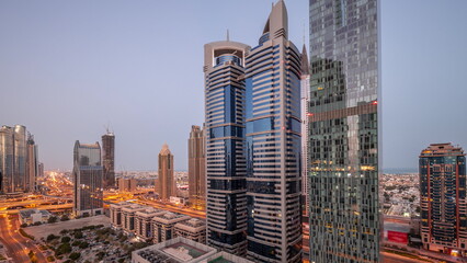 Obraz premium Aerial view of Dubai International Financial District with many skyscrapers night to day timelapse.
