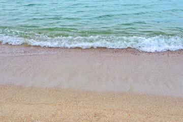 Sea coast and moving wave at the sandy beach for background and inspirational text.
