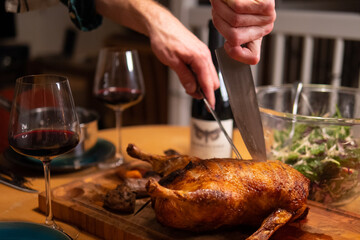 Man cutting into a roasted duck with a knife for a dinner party in Denmark