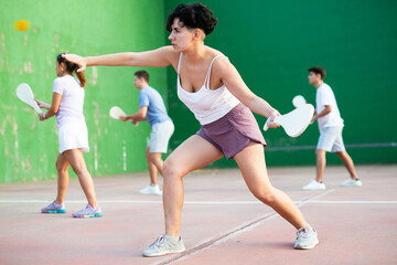 Latin woman serving ball with paleta during Basque pelota game outdoors. Woman playing pelota on...