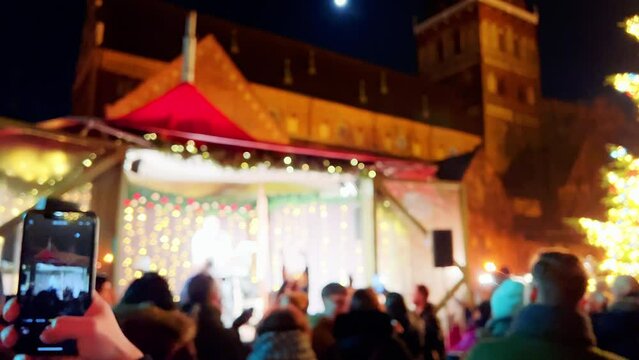 Defocused: Group of people dancing and cheering at a DJ performance outdoors before Christmas at night