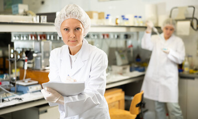 Female scientist engaged in research in chemical laboratory, noting results in chart. High quality photo