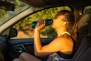 drinking water from a plastic bottle inside a car