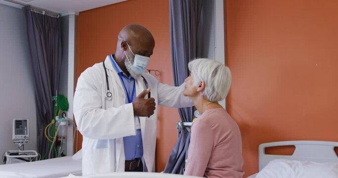 African american male doctor using penlight examining the eyes of senior caucasian female patient