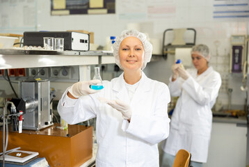 Concentrated woman scientist chemist works with liquids in beaker in science laboratory