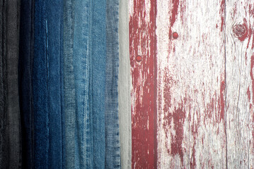 Obraz premium Stack of different jeans on wooden table. Space for text