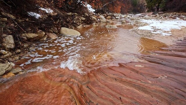 Water flowing downstream over textured sandstone in Zion during the winter season.