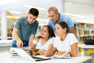 Obraz premium Group portrait of smiling positive engaged in research, working together in public library