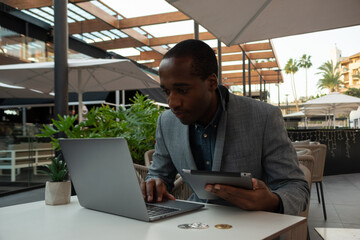 Bitcoin trader monitors the market through laptop and tablet with full concentration.