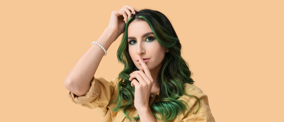Beautiful young woman with unusual green hair on beige background