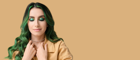 Beautiful young woman with unusual green hair on beige background with space for text
