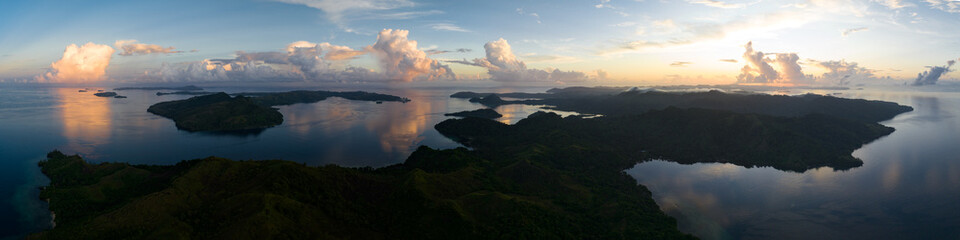 Sunrise illuminates clouds that drift over the calm waters of the Solomon Islands. This scenic region is known for its high marine biodiversity and World War II history.