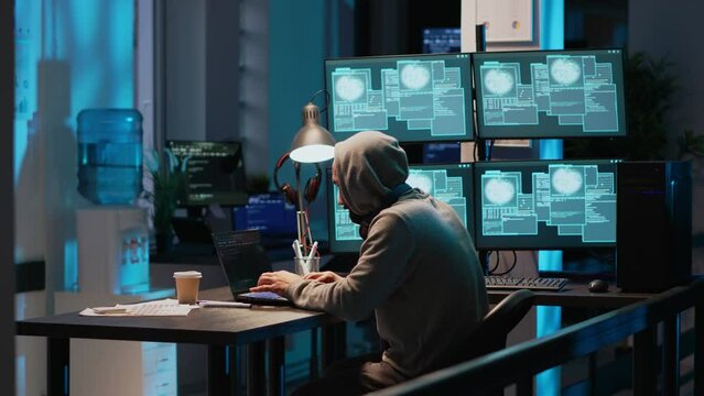 IT fraud criminal hacking security system to steal big data, doing cyberattack and ransomware. Coding virus to create malware and break into database servers, using multiple monitors.