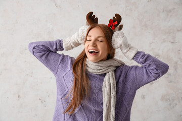 Young redhead woman in reindeer horns on light background