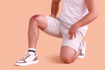 Man with bruise on knee against beige background