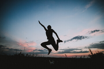 Fototapeta na wymiar woman jumping with joy against sunset sky