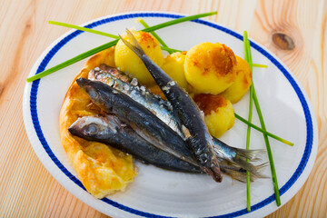 Dish of tasty fried anchovy with potato croquettes and cake served on plate